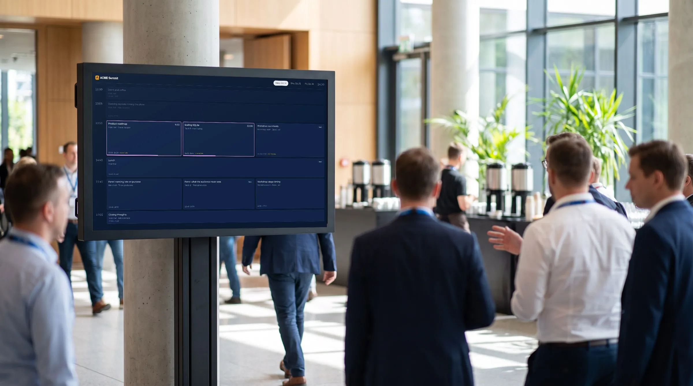 Illustration of a conference foyer: a display on a stand shows CueStride's real attendee agenda, in a navy screen theme, while attendees walk past.